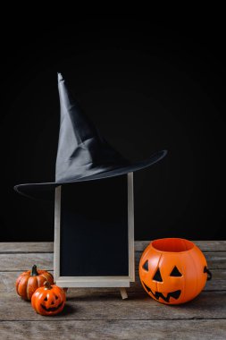 Cadılar Bayramı arka plan. kara tahta stand, ahşap zemin ve siyah arka plan üzerinde Halloween Pumpkins ile cadı şapka