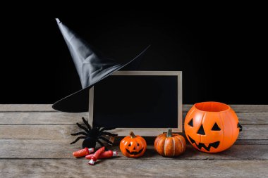 Cadılar Bayramı arka plan. standı, cadı şapkası, Siyah örümcek kara tahta ahşap zemin ve siyah arka plan üzerinde Halloween Pumpkins ile