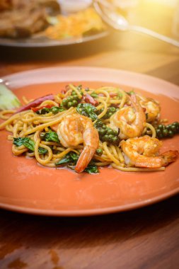 Acılı spagetti deniz ürünleri Tay gıda turuncu çanak (spagetti Pad Kee Mao) tarzda ahşap masa üzerinde tavada kızartılmış