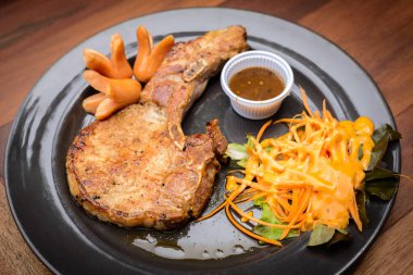 Izgara domuz kaburga pirzola biftek (domuz eti biftek) hizmet ahşap masa kil tabakta sebze ile