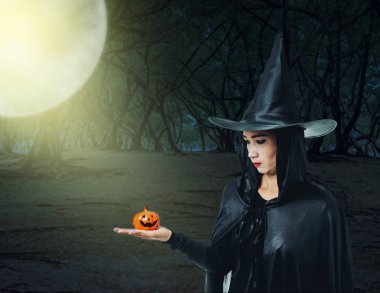 Karanlık bir orman ay ışığında içinde siyah korkunç cadı halloween kılık Holding Cadılar Bayramı Balkabağı kadın portresi