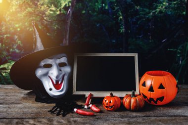 Cadılar Bayramı arka plan. Ürkütücü kabak, cadı maskesi, kara tahta ay ve karanlık orman ile ahşap zemin üzerinde. Cadılar Bayramı tasarımı ile boşaltmak