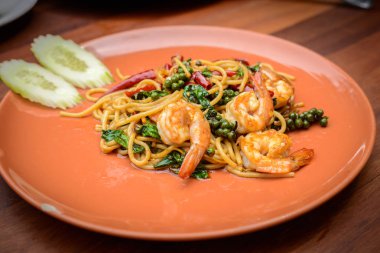Acılı spagetti deniz ürünleri Tay gıda turuncu çanak (spagetti Pad Kee Mao) tarzda ahşap masa üzerinde tavada kızartılmış