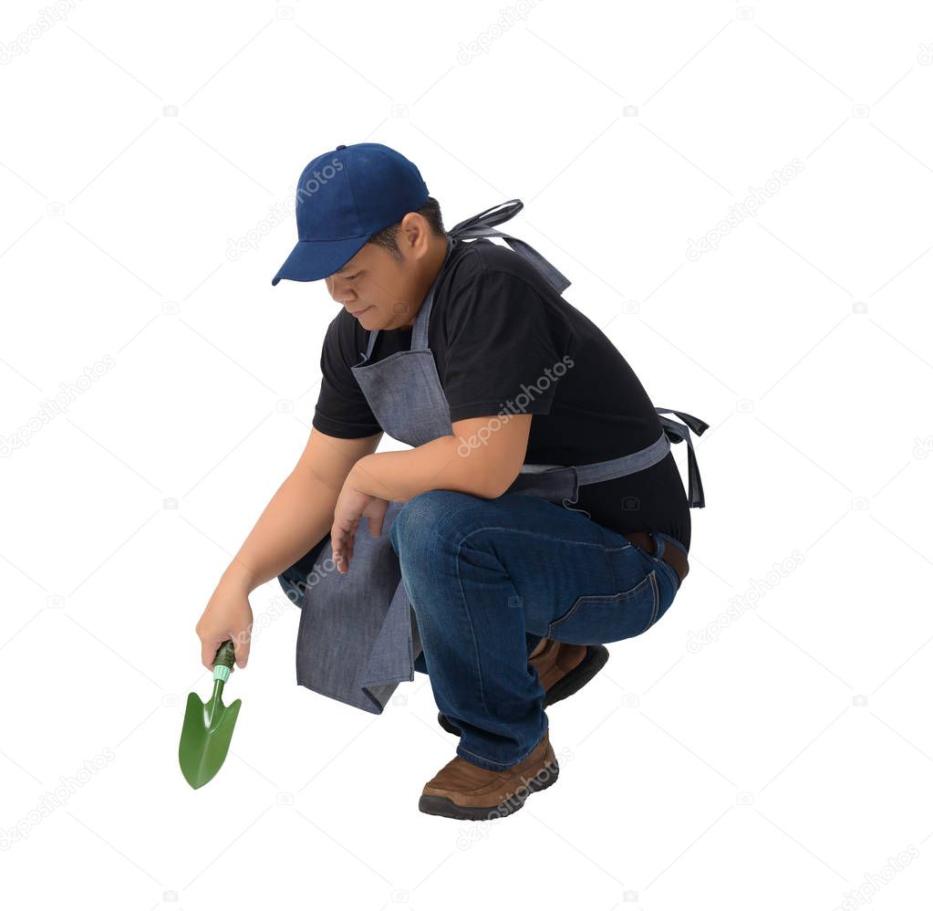 worker man or Serviceman in Black shirt with apron sitting and holding Shovel for Cultivators isolated on white background clipping path. Hand-made, DIY, Garden concept