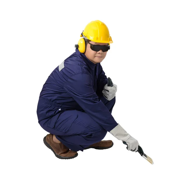 工人在机械连身裤坐在和持有油漆刷与头盔 保护手套和安全护目镜查出的白色背景裁剪路径 — 图库照片
