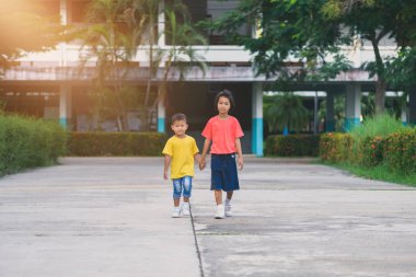 Küçük Asyalı erkek ve kız kardeşlerim el ele yürümek. aşk aile kavramları