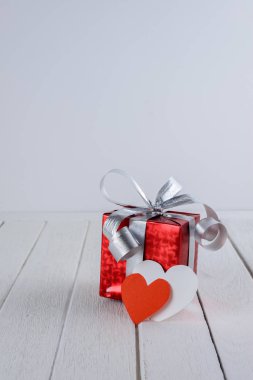 Kırmızı hediye kutusu beyaz ahşap masa ve kopya alanı metni üzerinde kalp şeklinde. Saint Sevgililer günü kavramı