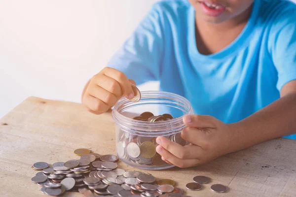 Cute asian boy putting coins into Glass bowl on white background — ストック写真