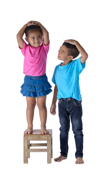 Menino e menina medindo sua altura isolado em bac branco — Fotografia de Stock