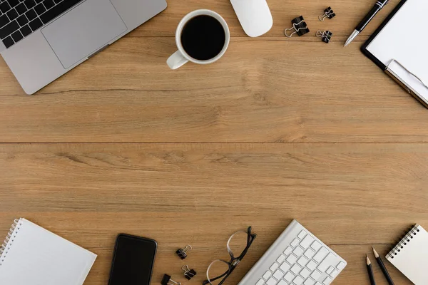 フラットレイアウト 最上階の木製のオフィスデスク 木製テーブルの背景にコピースペース付きの空白のクリップボード ラップトップ スマートフォン 金属クリップ コーヒーカップオフィス用品とワークスペース — ストック写真