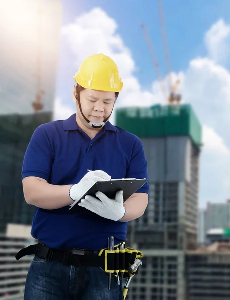 男性建築請負業者建設進捗状況フォームに署名倉庫の背景をぼやけている — ストック写真