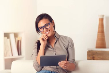 Evde bir kanepede oturan digialt tablet kullanma gülümseyen kadın portresi