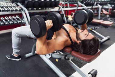Halter ağırlık mı bir spor salonunda bir kavram sağlık ve fitness konusunda üst vücut görünümü kadar yakın bir bankta yalan vücut geliştirmeci