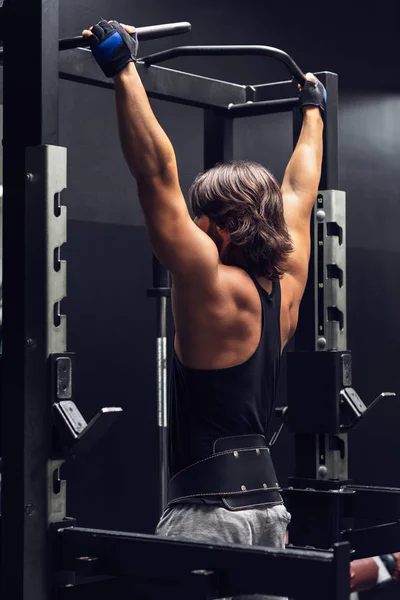 运动肌肉的人在健身房做拉 Ups 从后方观看 以加强他的肌肉 — 图库照片