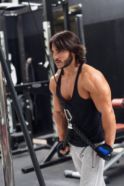 Yan görünümü üst vücut egzersiz spor sırasında triceps açılan kablo makinede egzersiz kararlı bir genç adam portresi