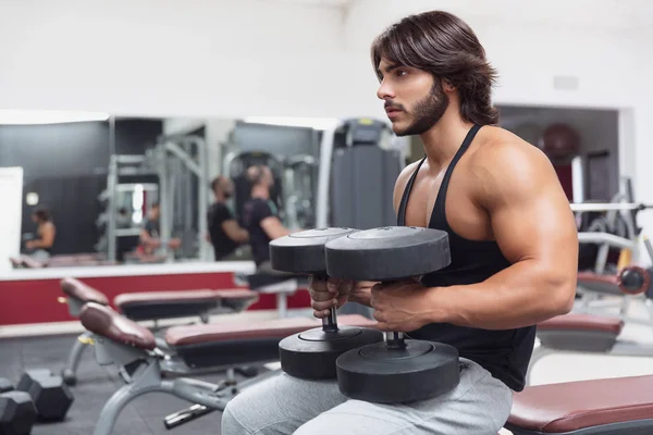 Bodybuilder Der Einem Fitnessstudio Auf Einer Bank Sitzt Und Hantelgewichte — Stockfoto