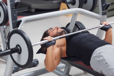 Halterci veya vücut geliştirmeci bir sağlıklı aktif yaşam tarzı ve fitness kavram eğitimi sırasında bir spor salonunda bir halter ağırlık kaldırma bir Bank üzerinde yalan