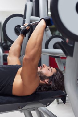 Halterci veya vücut geliştirmeci bir sağlıklı aktif yaşam tarzı ve fitness kavram eğitimi sırasında bir spor salonunda bir halter ağırlık kaldırma bir Bank üzerinde yalan