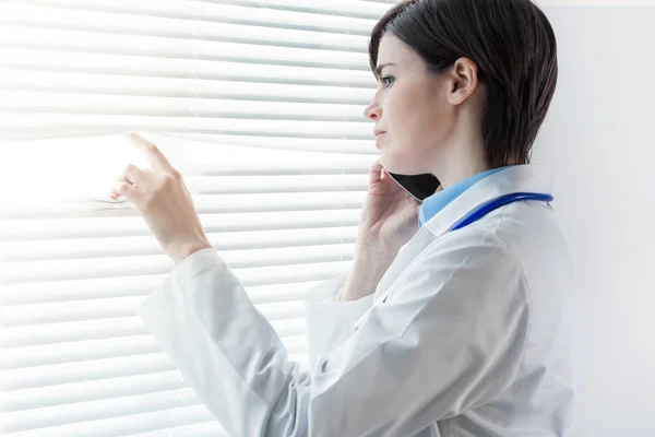 Preocupado Médico Mulher Pensativa Frente Uma Janela Com Persianas Louver — Fotografia de Stock