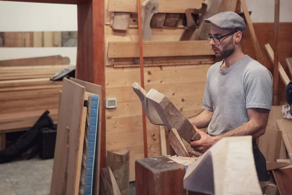 Marangozluk çalışan adam gözlüklü, gri t-shirt ve cap de ahşap mobilya detay atölye ayakta onun elinde arıyor