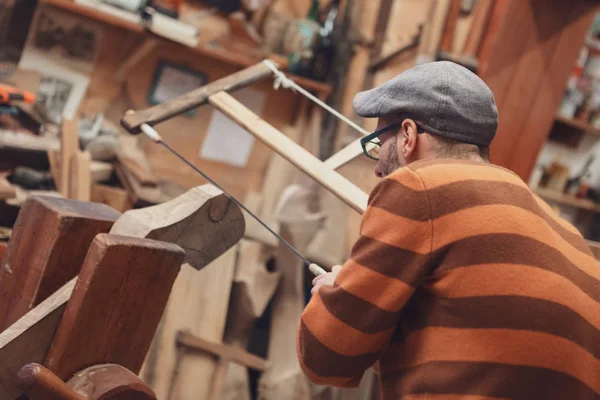 Eski moda kap ve soyulmuş kazak ahşap doğrama atölyesinde vintage ahşap yay testere aracı yandan görüntülendi ayrıntılarıyla testere marangoz