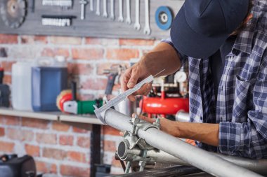 Metal işçisi metal borunun ölçümlerini alıyor.