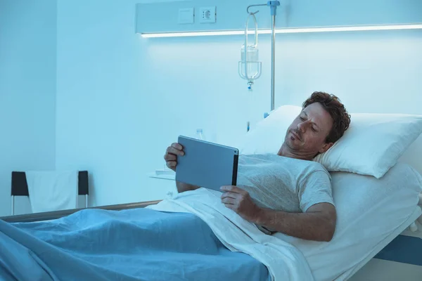 침대에 이루는 환자는 자신의 디지털 태블릿으로 비디오를 — 스톡 사진