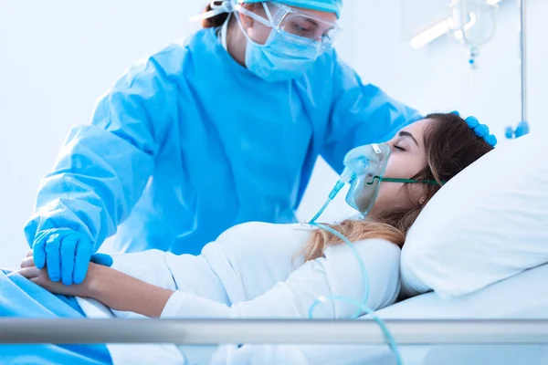 Nurse comforting a sick patient wearing a mask for positive pressure oxygen for respiratory diseases during the Covid-19 pandemic in the ward as she lies in bed