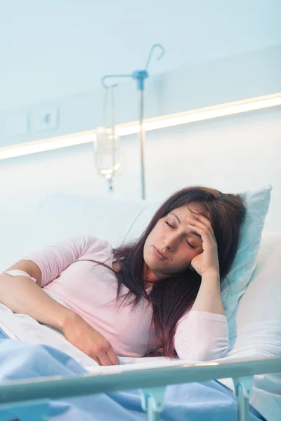 Young female patient lying in a hospital bed at night and she is suffering