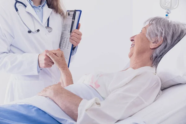 Uśmiechnięta Kobieta Lekarz Lub Pielęgniarka Pocieszająca Starszą Kobietę Łóżku Wyciągającą — Zdjęcie stockowe
