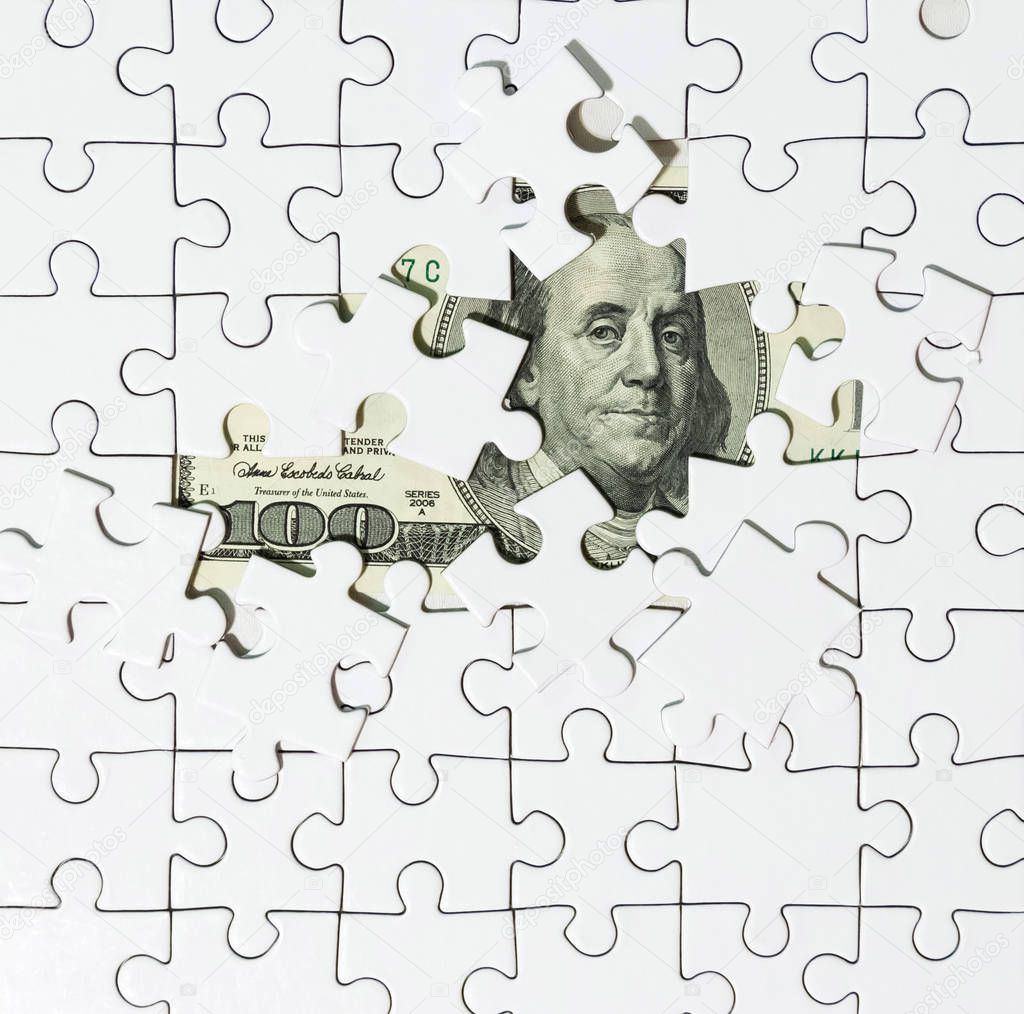 Background of white puzzle in the center of which the banknote in 100 dollars