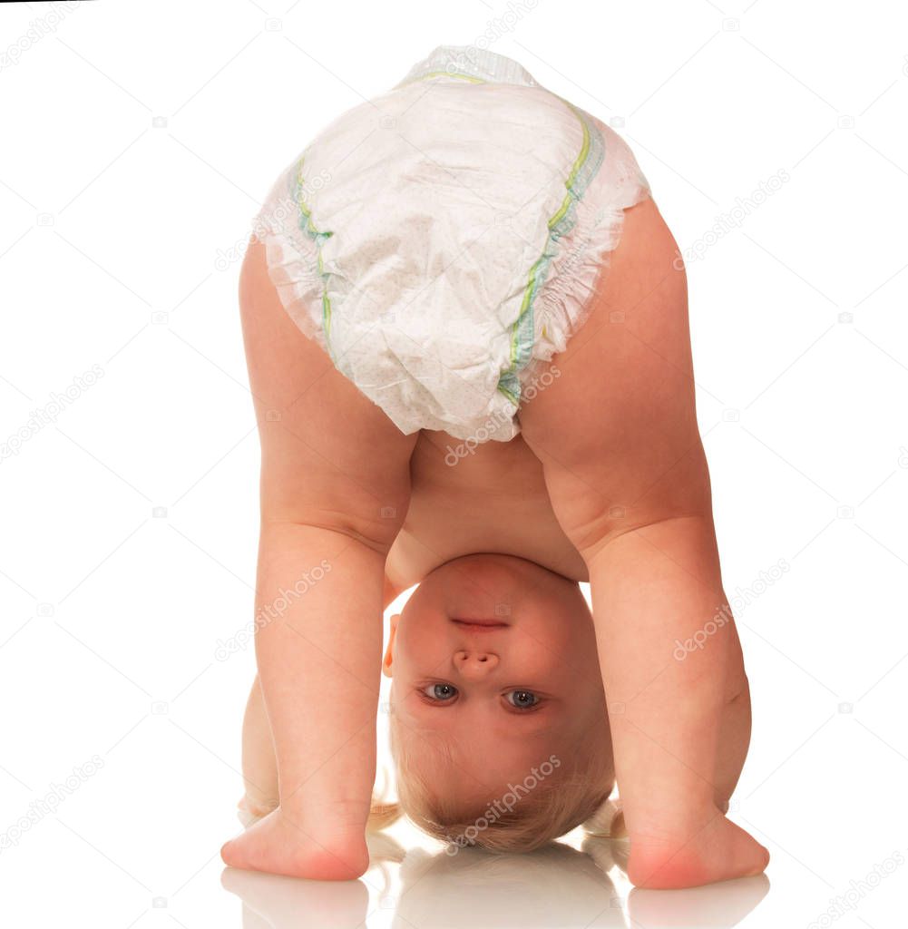 Little smiling baby in a diaper upside down isolated on white background