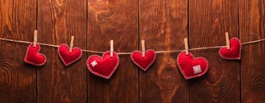 Sevgililer günün kutlu olsun. El yapımı keçe kalp ahşap arka plan üzerinde bir ip üzerinde clothespins ile bağlı