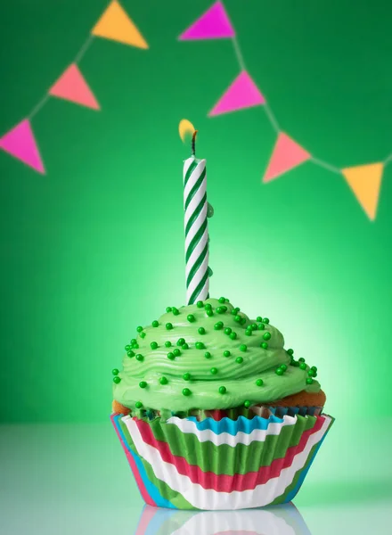 Cupcake festivo con crema verde e candela accesa su un luminoso — Foto Stock