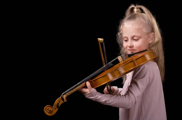 Красивая маленькая блондинка, играющая на скрипке на черном фоне — стоковое фото