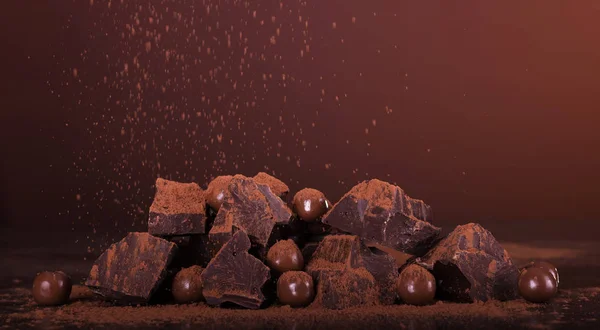 Организация кусочки шоколада и круглые конфеты посыпанные какао порошок на коричневый — стоковое фото