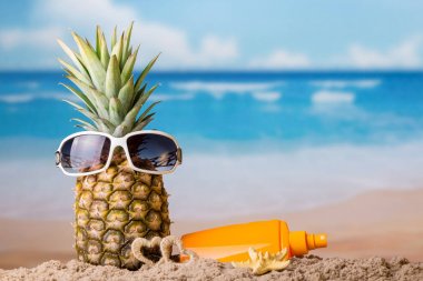 Dinlenme kavramı. Kum ve krem güneş gözlüğü içinde ananas s