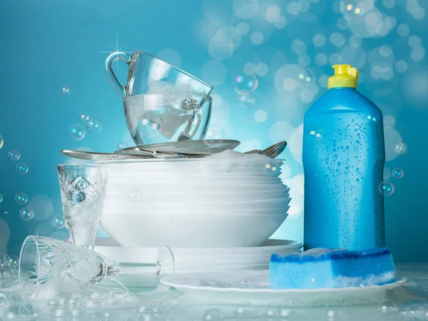 Clean washed dishes, dishwashing and soap bubbles on blue