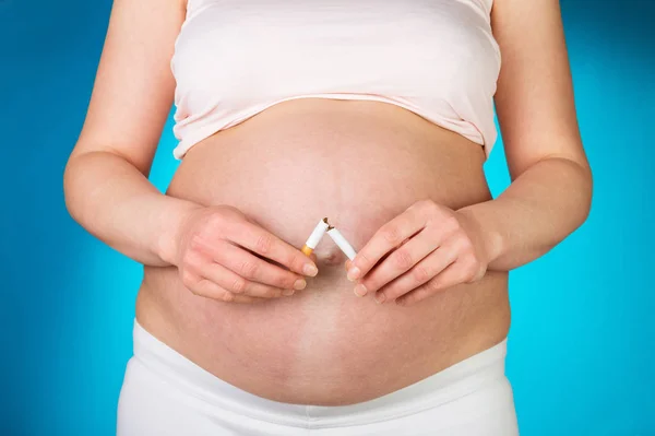 Concepto de dejar de fumar. Mujer embarazada con un primer plano de cigarrillo roto — Foto de Stock