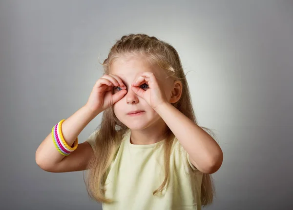 灰色の彼の指から双眼鏡を通して見ている小さなかわいい女の子 — ストック写真