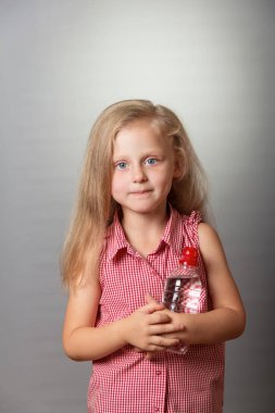 Gri arka plan üzerinde delici gözleri ve su şişesi ile Gülümseyen küçük kız