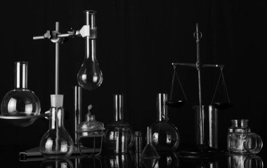 Şişeler ve test tüpleri, kimyasal ölçekler ve brülör kimyasal laboratuvar çeşitliliği. Siyah-beyaz fotoğraf