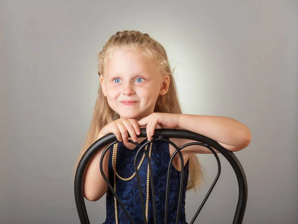 Beautiful little girl dressed in a dark dress and jewelry on gray — Stock Photo, Image