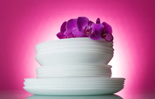 Schoon gewassen witte platen op roze achtergrond en een orchideeën tak — Stockfoto