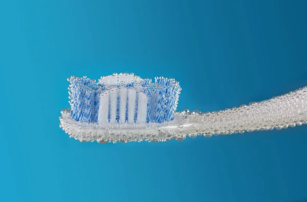 Toothbrush with the striped bristles on blue background with bubbles — Stock Photo, Image