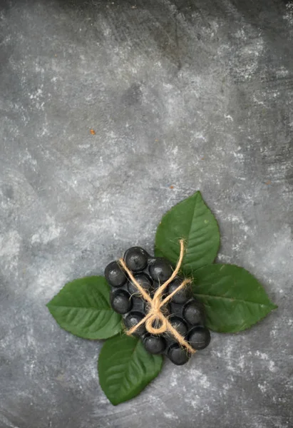 Black charcoal volcanic soap and green leaves on grey background. Put your text.