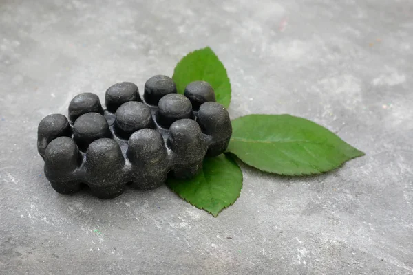 Black charcoal volcanic soap and herbal leaves red rose petals on grey background. Put your text.