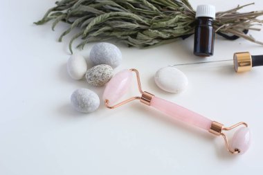 Beyaz arka planda duran pembe yüz silindiri. Güzellik aletleri. Yüz için Quartz silindirli masaj aracı.