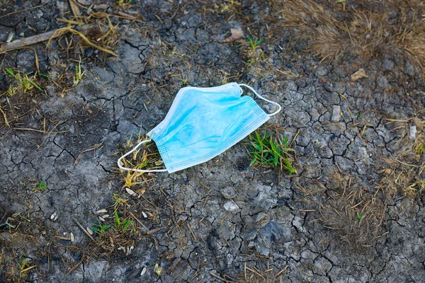 Medical face mask laying on the ground at the street. Used face mask dropped on the ground outside at the street. Pollution concept. Coronavirus covid concept.