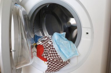 Çamaşır makinesinde bir sürü pamuk yüz maskesi var. Kirli maskeler yıkanmaya hazır..